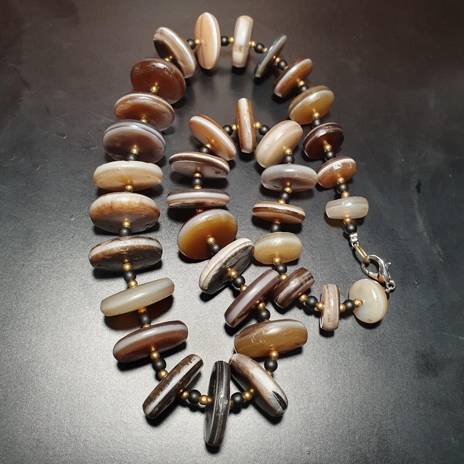 "Vintage necklace featuring a rare collection of ancient agate stone beads from the Himalayan region of India, strung together in a single line of disc-shaped beads, showcasing their natural beauty and historical significance."