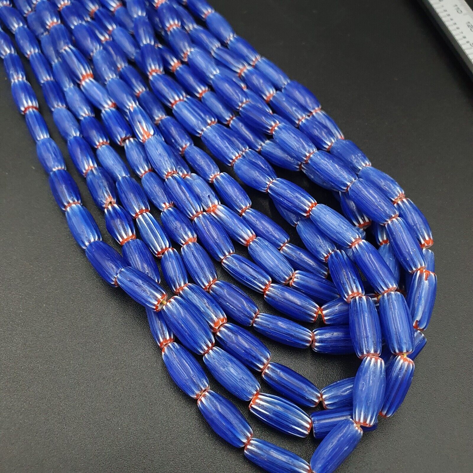 "Image of 3 long strands of vintage blue chevron beads, showcasing a stunning Venetian glasswork technique and African-inspired style, perfect for adding a statement touch to any outfit or jewelry collection."