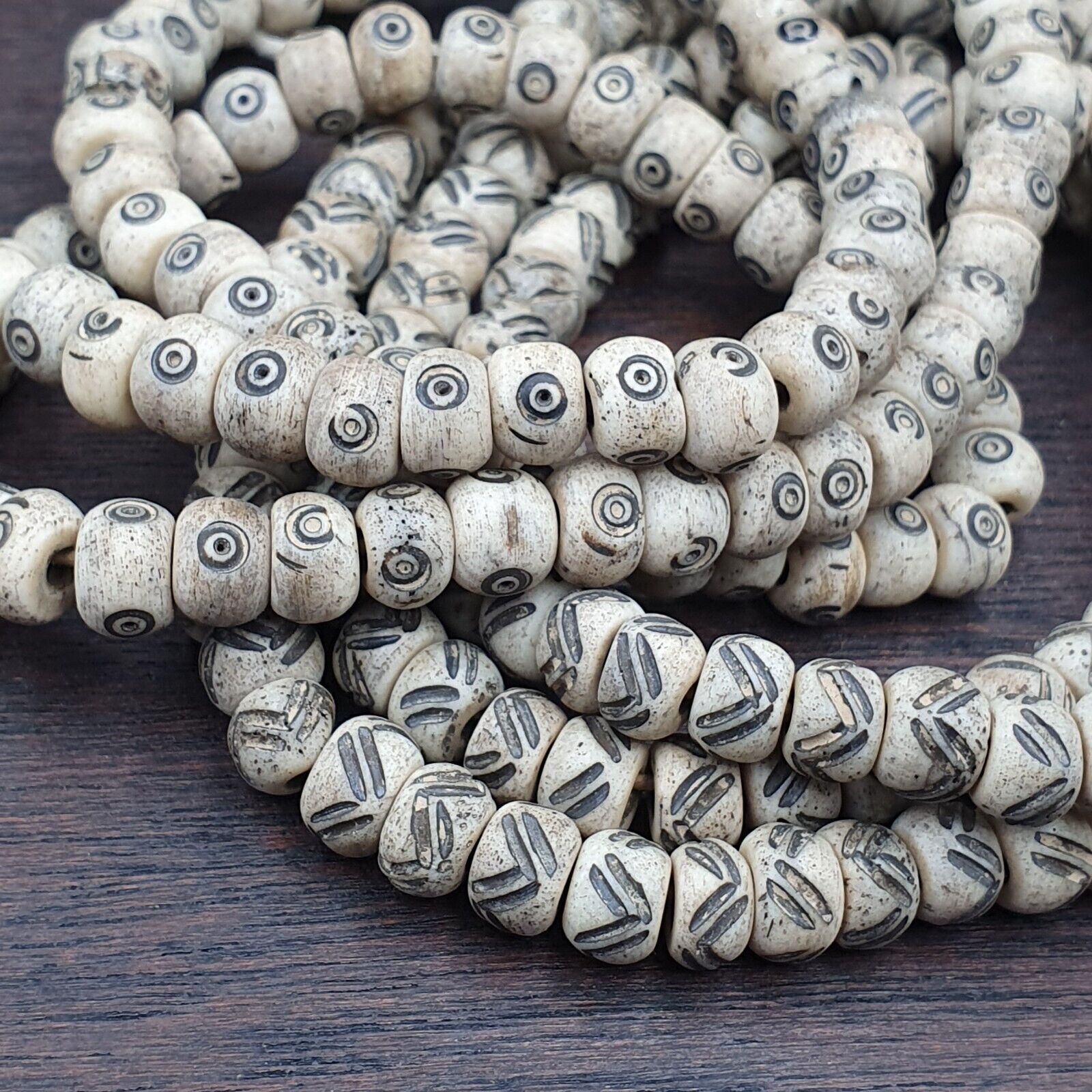 "Two vintage Tibetan-Chinese carved necklace strands, featuring intricately decorated beads with tribal designs. These unique and rare beads showcase exceptional craftsmanship and cultural heritage, making them a valuable addition to any jewelry collection or cultural artifact display."