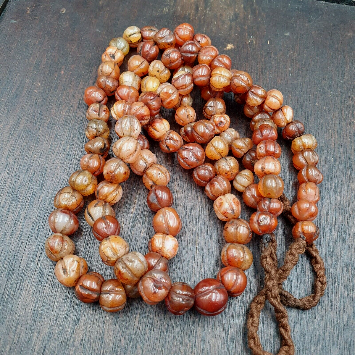 "Vintage Himalayan Tibetan Carnelian Carved Agate Melon Shape Beads Necklace. A stunning necklace featuring intricately carved agate beads in a melon shape, with a beautiful carnelian stone accent. The beads showcase traditional Tibetan craftsmanship, with a warm, earthy tone that evokes the Himalayan region's rich cultural heritage."