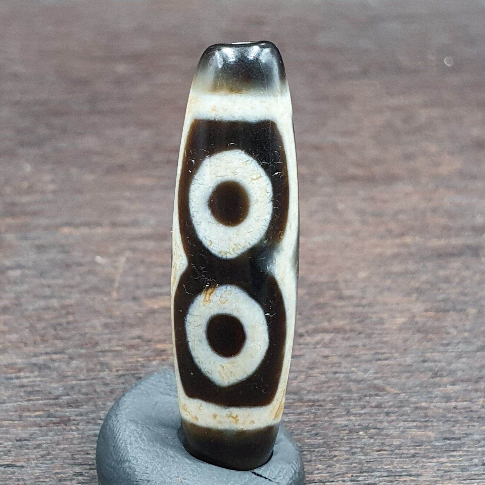 "Unique three-eyed agate bead from the Himalayas, featuring an intricate pattern and believed to possess spiritual powers, a rare find for collectors and enthusiasts."