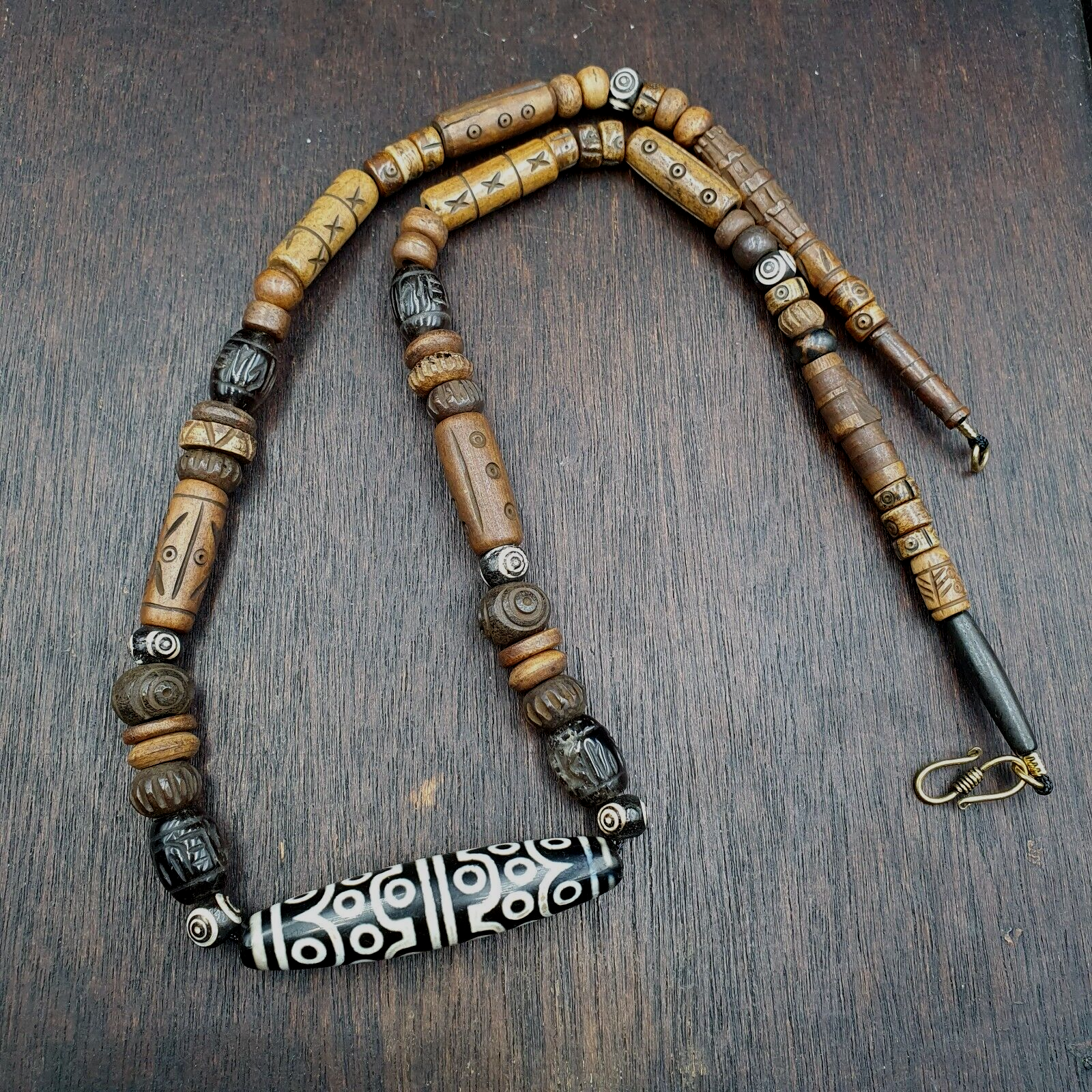 "Vintage Tibetan Himalayan Agate and Yak Bone Amulet Necklace. A unique and culturally significant necklace featuring a intricately carved agate bead with 24 eyes, accompanied by yak bone accents. This traditional Tibetan amulet is said to bring protection and good fortune, and showcases the region's rich spiritual heritage."
